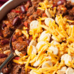 bison chili with cheese and crackers on top of it.