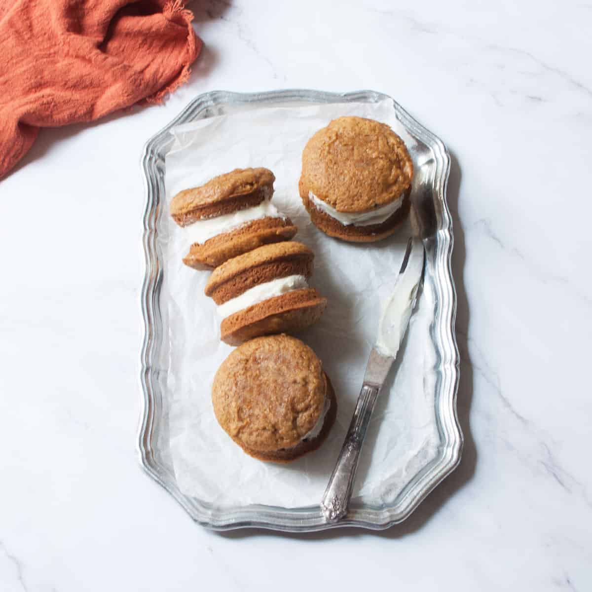 Amish Pumpkin Whoopie Pies on a silver tray with a kinfe on it. 