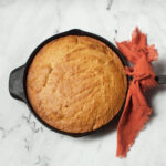 Cast iron skillet pumpkin bread on a marble background.