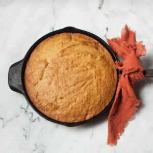 Cast iron skillet pumpkin bread on a marble background.