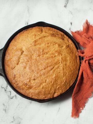 Cast iron skillet pumpkin bread on a marble background.