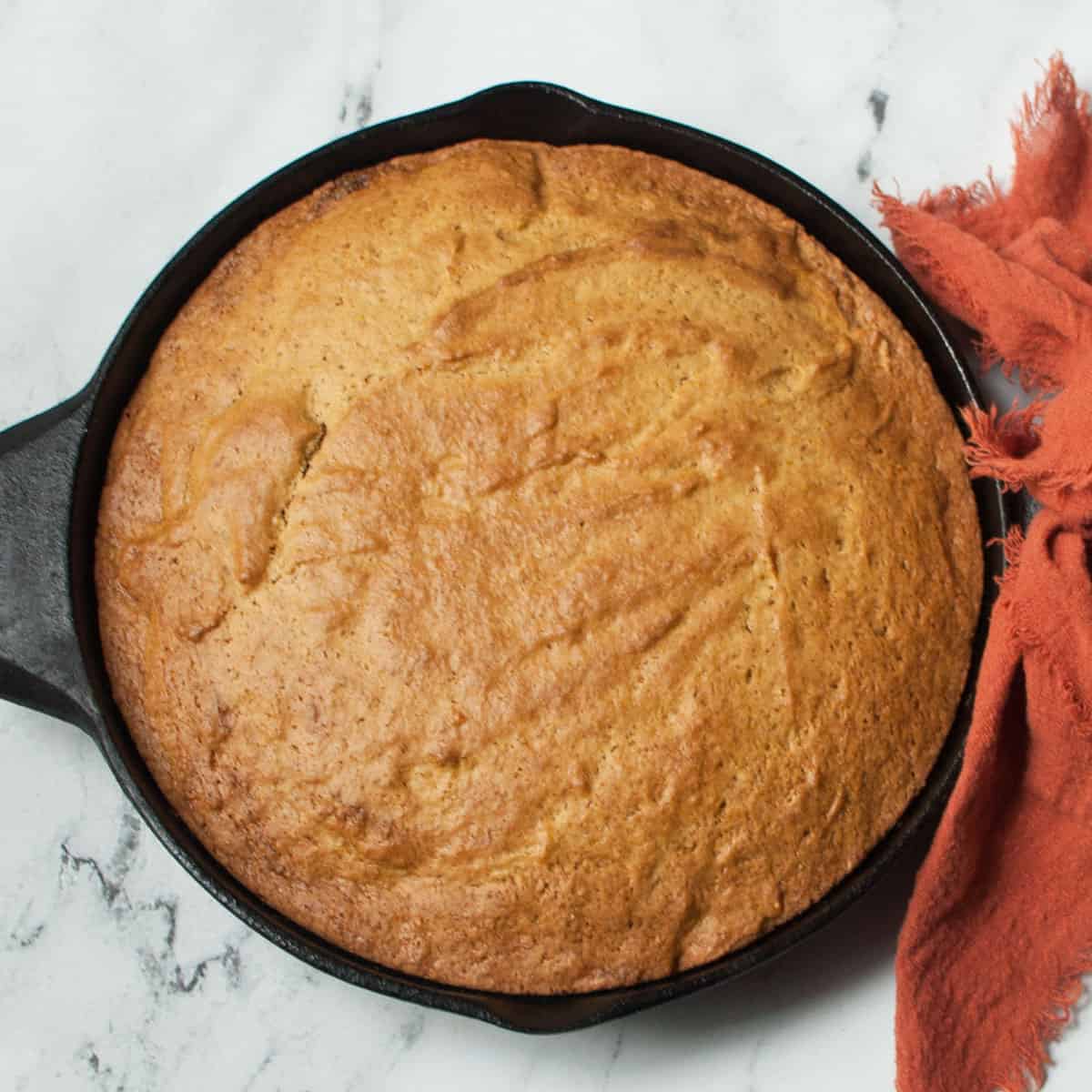 Cast iron skillet pumpkin bread on a marble background.