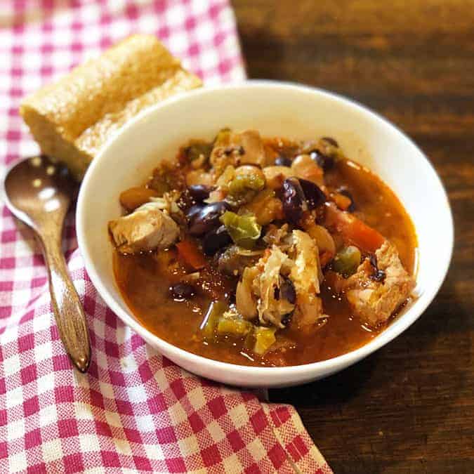 bowl of chipotle chicken chili with cornbread and a spoon