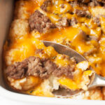 A large spoon scooping a breakfast casserole.
