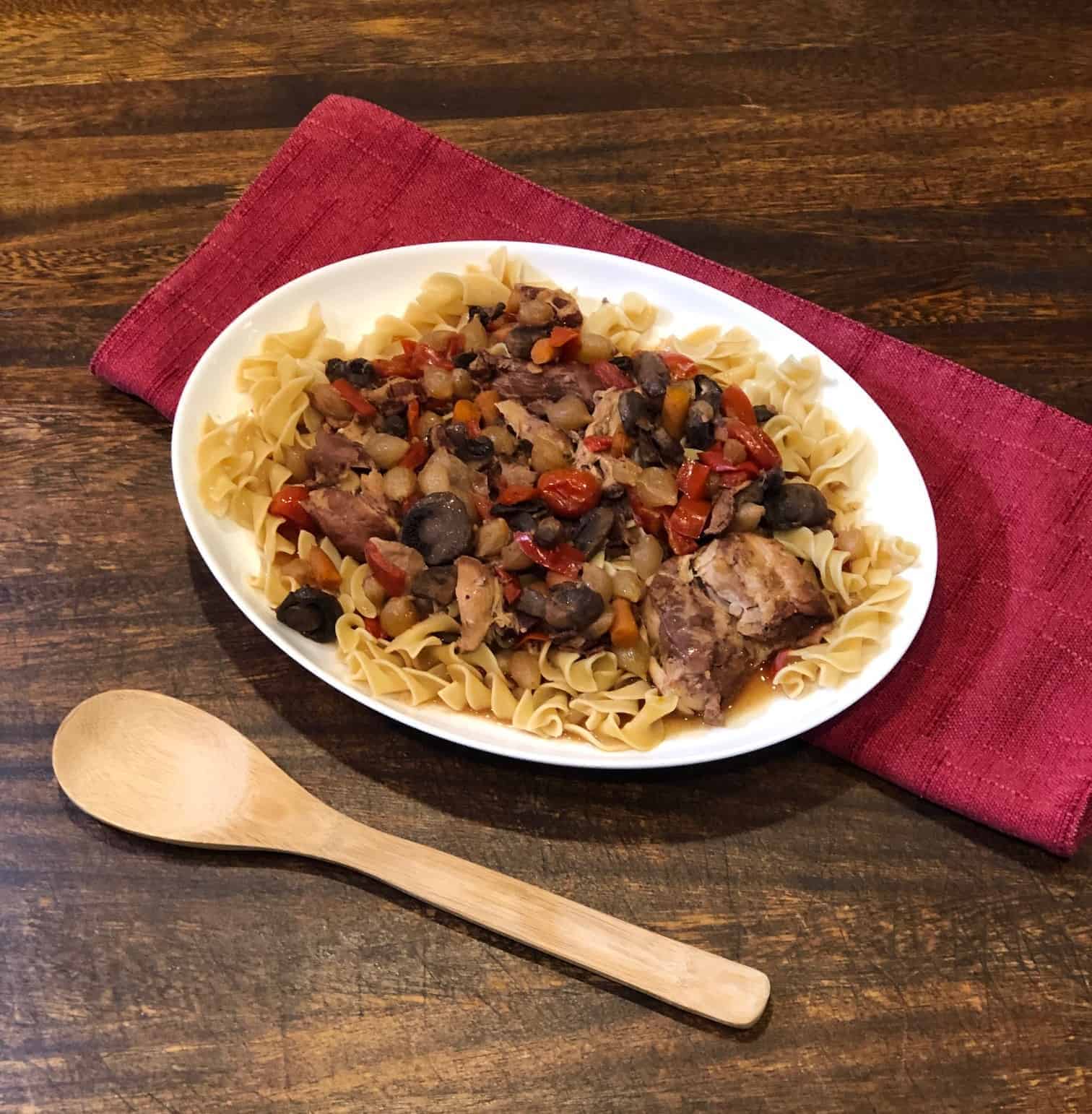 coq au vin on a white plate with a wooden spoon
