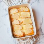 cheesy butternut squash casserole in a casserole dish on a white striped linen