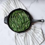 cast iron skillet green beans on a white striped linen