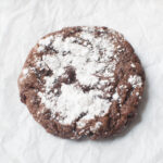 A chocolate orange crinkle cookie on a white background.