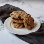 Copycat Otis Spunkmeyer Oatmeal Raisin Cookies stacked on a white plate with a gray linen
