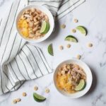 Crockpot White Chicken Chili in two small white bowls surrounded by oyster crackers and lime wedges