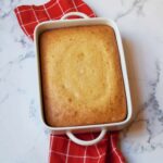Yellow Cake Mix Corn Bread in a white pan with a red tea towel