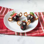 reindeer chocolate covered strawberries on a white plate with a red linen