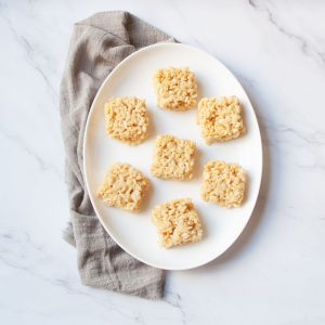 Rice Crispy Treats made with Jumbo Marshmallows on a white oval plate with a gray linen
