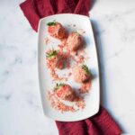strawberry crunch covered strawberries on a white plate with a red linen