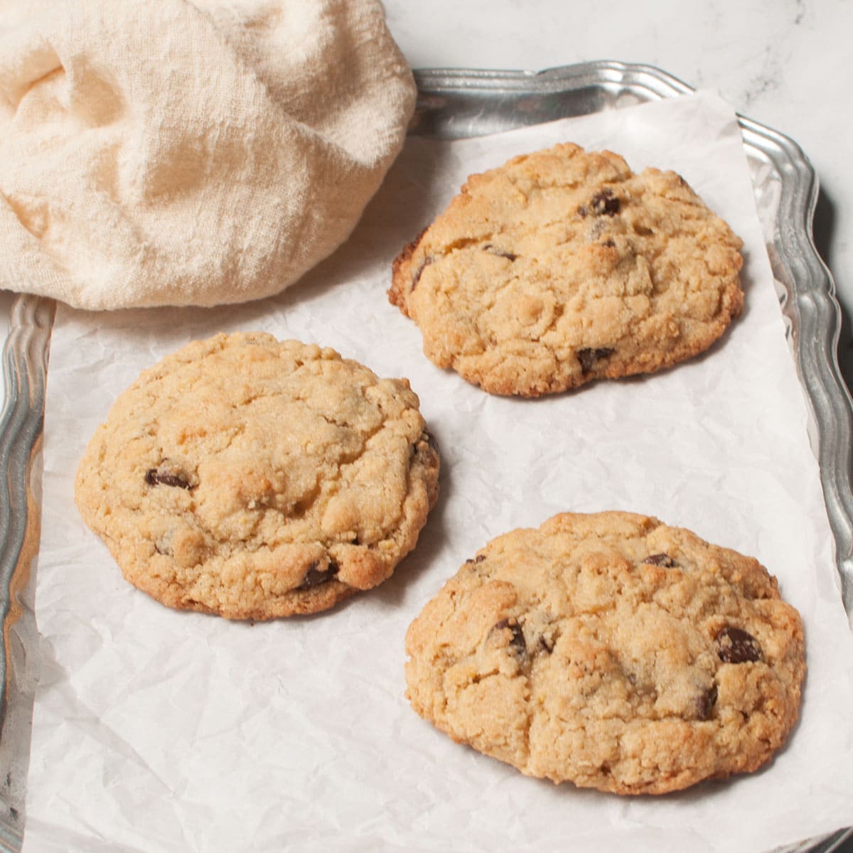 Sourdough chocolate chip cookies on a tray with a cream linen.
