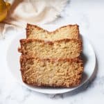 sourdough lemon loaf on a white plate with a tea towel