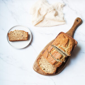Old Fashioned Banana Bread on a serving board with a white linen