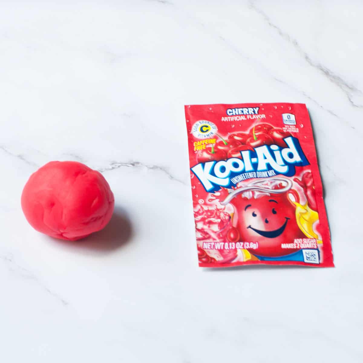 a red kool aid packet and small ball of red play dough
