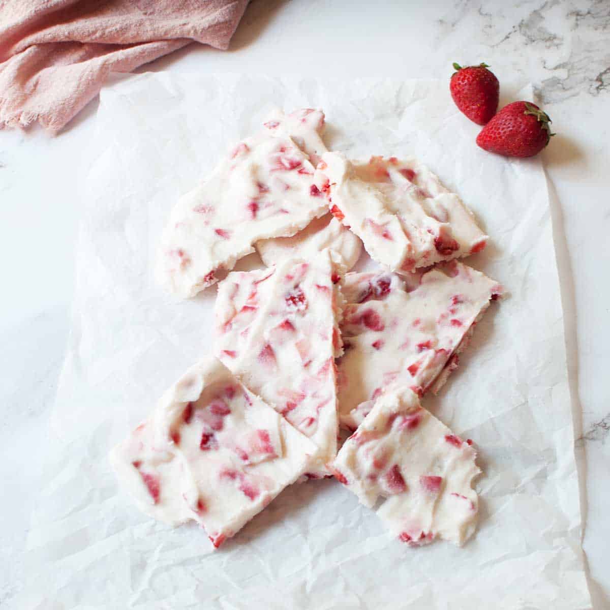 a pile of Greek Yogurt Breakfast Bark there are strawberries to the side