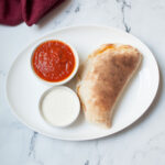dipping sauces on a plate with a calzone