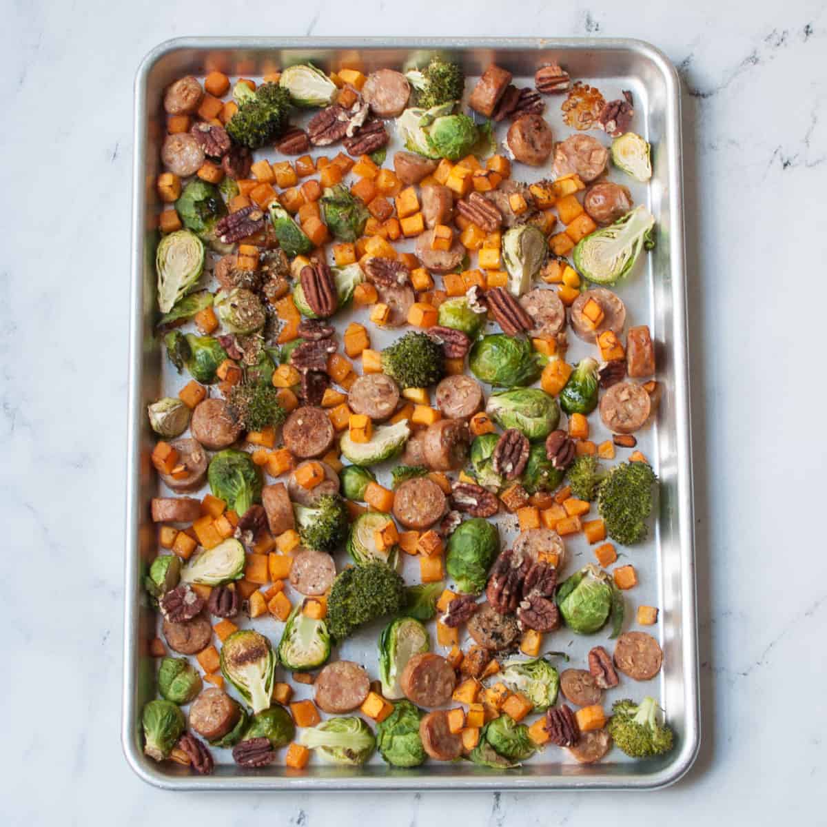 Harvest Sheet Pan Dinner (apple sausage, butternut squash, pecans, broccoli, and brussels sprouts) on a sheet pan