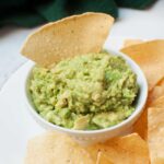 3 ingredient guacamole in a small white bowl with a chip