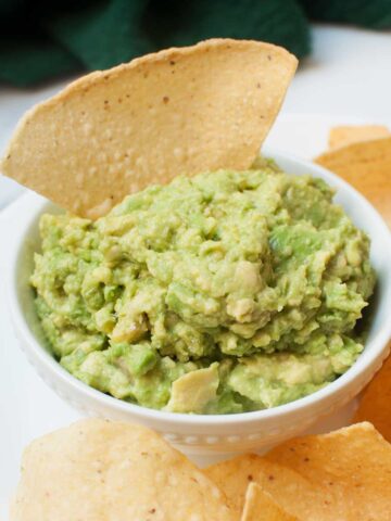 3 ingredient guacamole in a small white bowl with a chip
