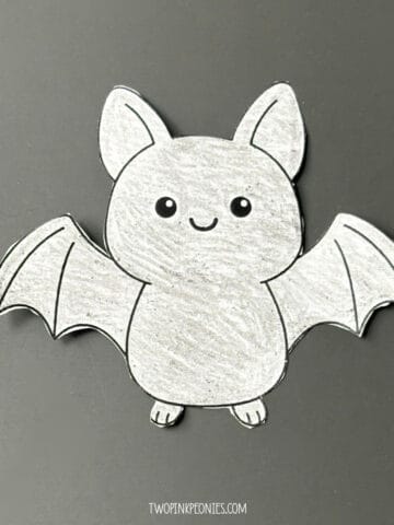 The large sized printable bat template colored in and cut out. It is sitting on a black background.