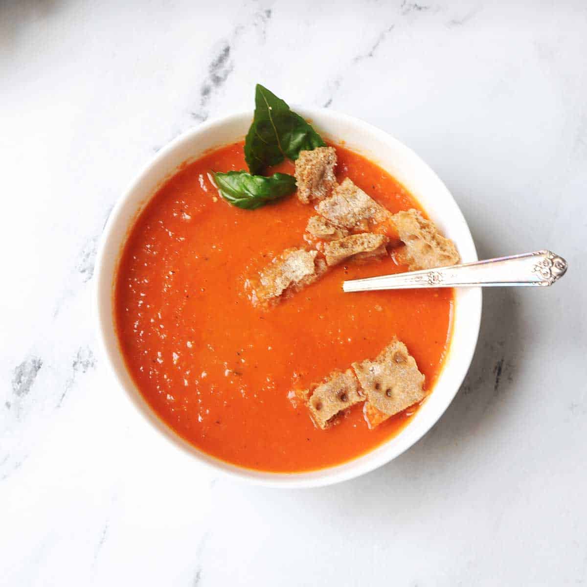 Copycat Panera Tomato Soup in a bowl with croutons and a spoon in it