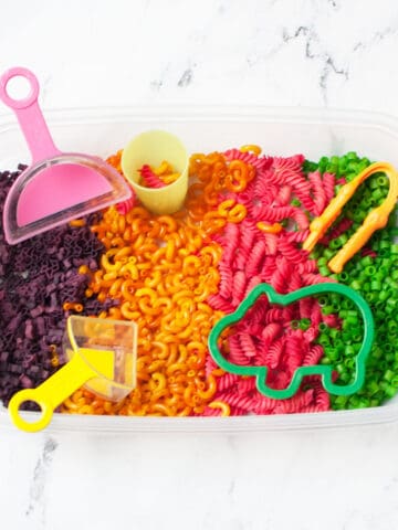 a colored pasta sensory bins with scoops and cookie cutters