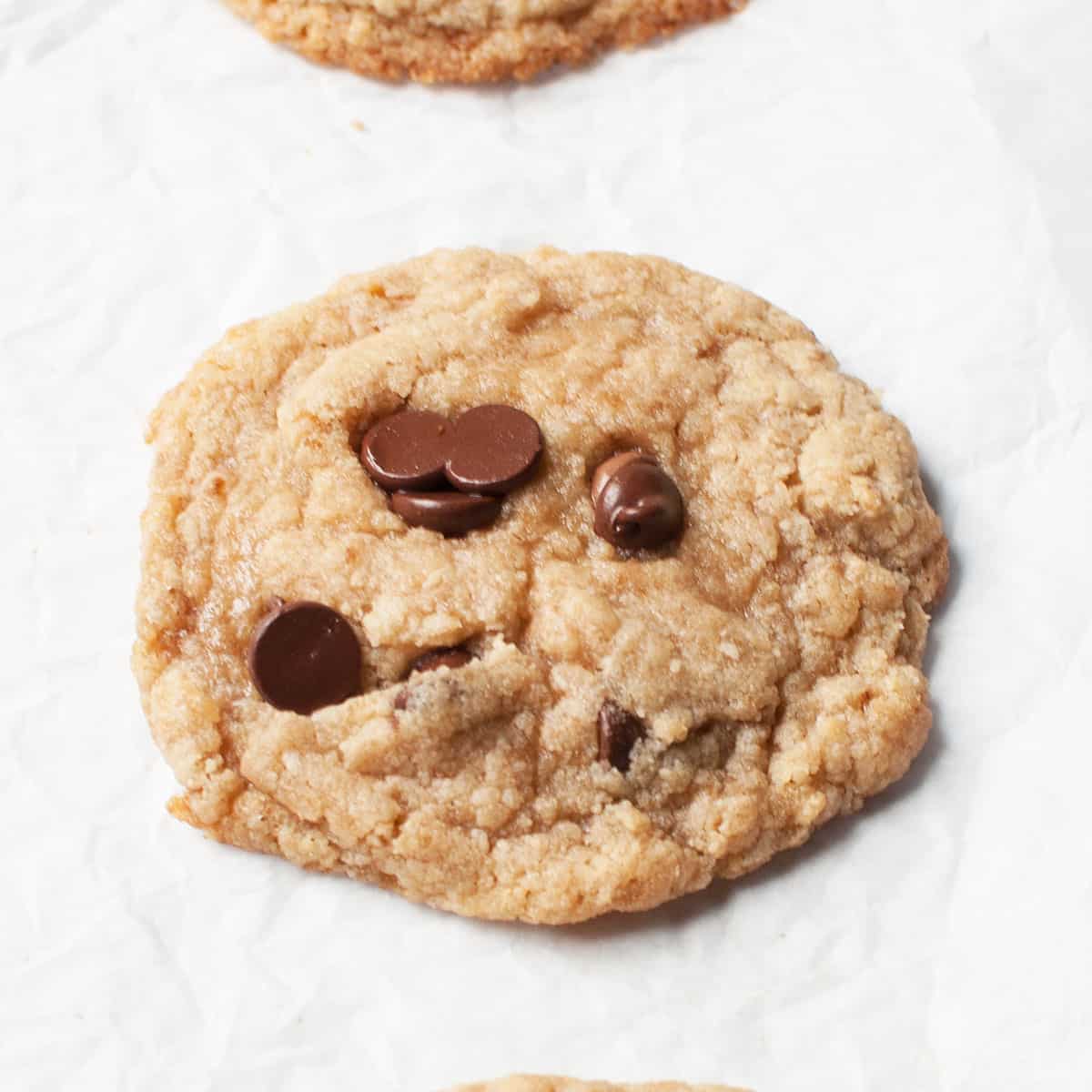A single chocolate chip cookie on a parchment paper.