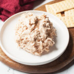 Copycat Chicken Salad Chick Barbie-Q chicken salad on a white plate which is sitting on a wooden tray.