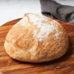 A loaf of sourdough bread on a wooden tray.