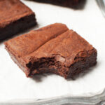 A brownie square with a bite taken out of it.