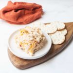 Copycat Chicken Salad Chick Kickin Kay Lynne chicken salad (chicken salad with bacon, cheddar, and pickled jalapenos in it) on a plate with crackers with an orange linen.