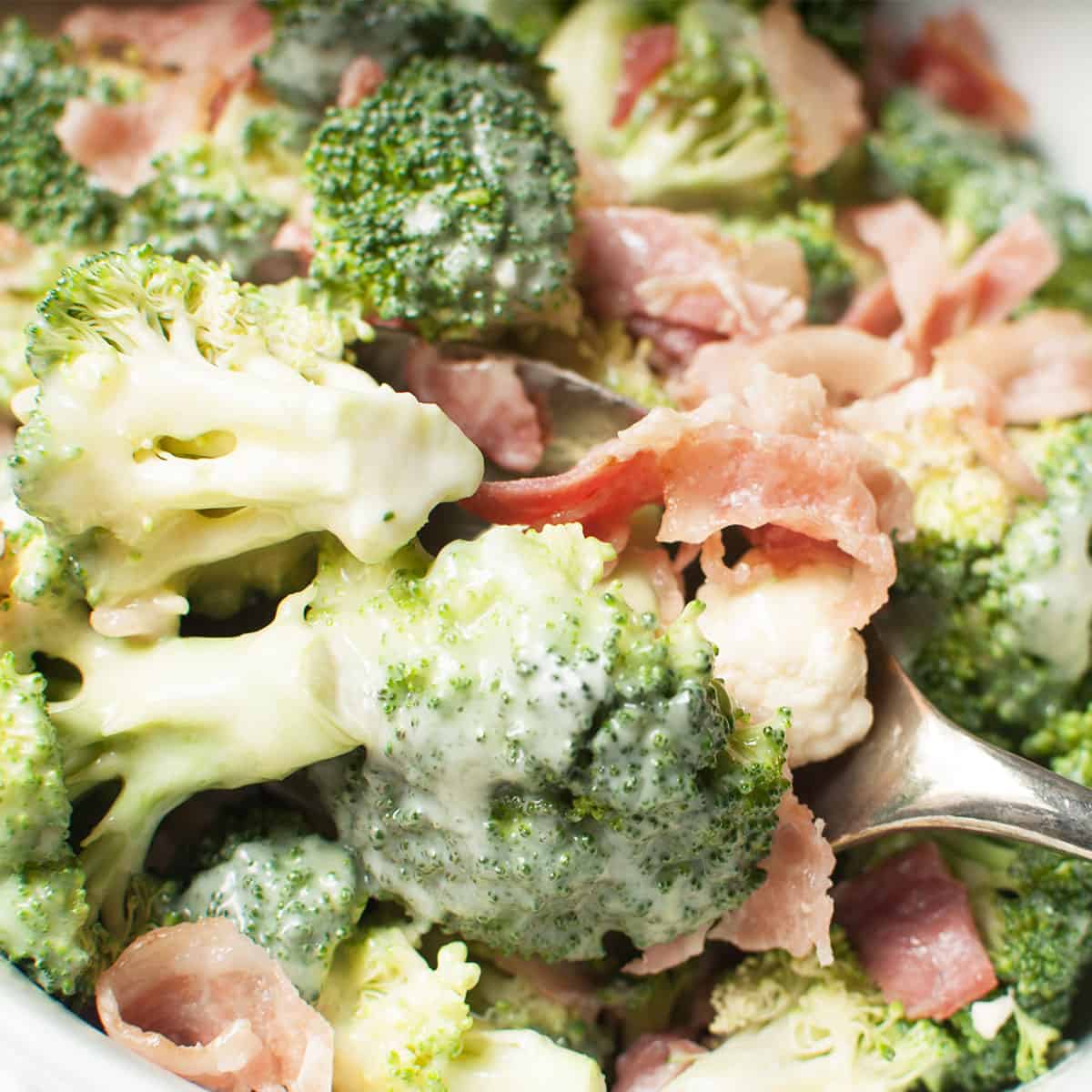 A spoon scooping Amish Broccoli and Cauliflower Salad.