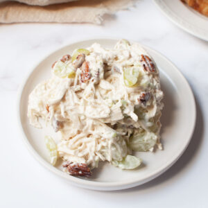 Amish chicken salad with pecans and grapes. The chicken salad is on a white plate.