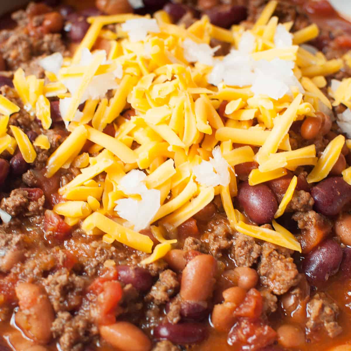 Upclose photo of bison chili wth cheese and onions on top of it.
