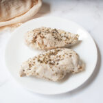 Italian seasoned chicken breasts on a white plate.