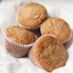 Jumbo banana muffins in a basket lined with a white linen.