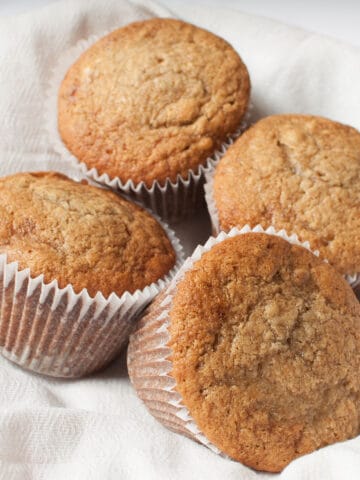 Jumbo banana muffins in a basket lined with a white linen.