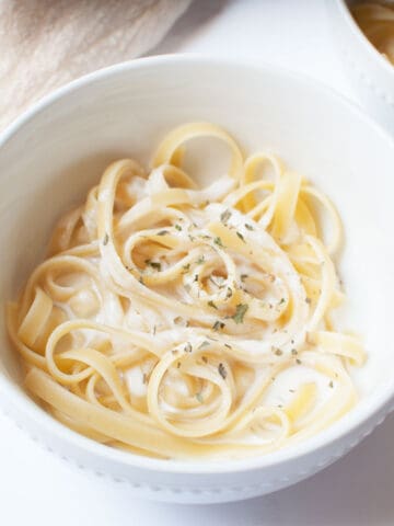 Copycat Fazoli's Alfredo Sauce with pasta in a white bowl.