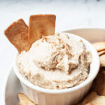 Close up view of a cream cheese based dip with cinnamon sugar chips in it.