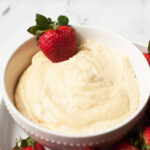 A white bowl filled with Amish fruit dip with a strawberry in it.