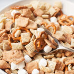 A spoon scooping Cinnamon Toast Crunch snack mix.