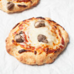 A small pizza with mushrooms on a white background.
