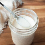 Ranch dressing in a mason jar with a small spoon in it.