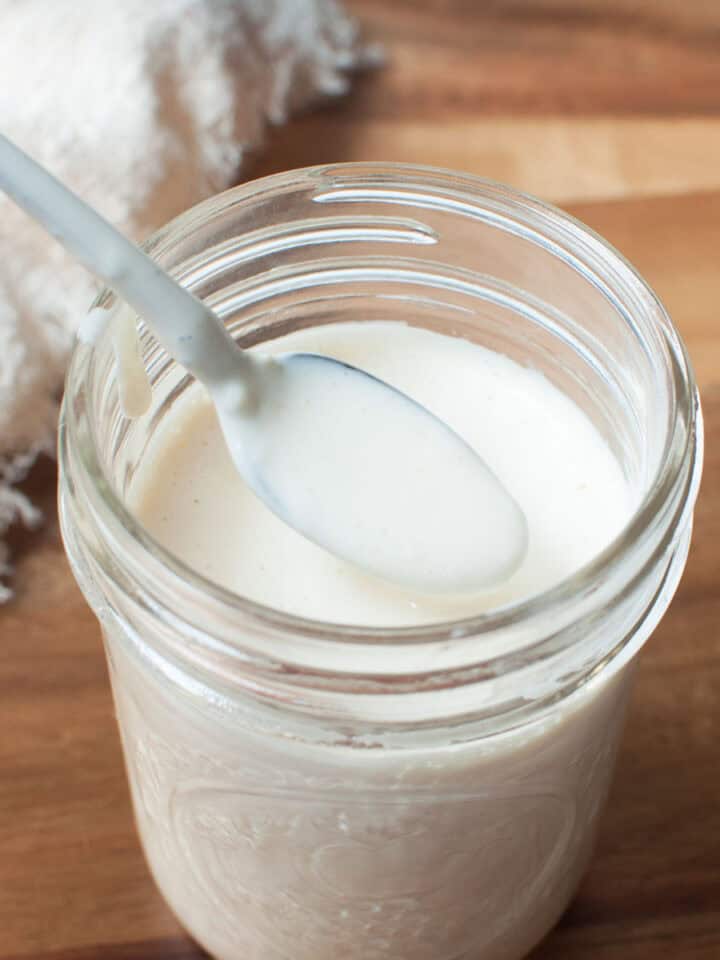 Ranch dressing in a mason jar with a small spoon in it.