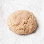 A single sourdough cinnamon cookie on a white background.