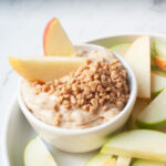 A close up view of fall fruit dip with apple slices in it and around it.